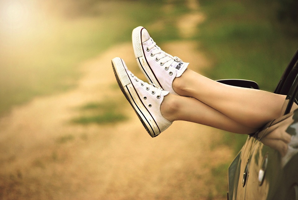 Feet resting out of stationary car window in relaxed manner.