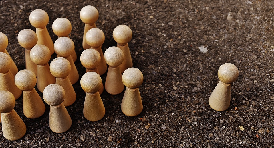 wooden figures, one apart from the group.