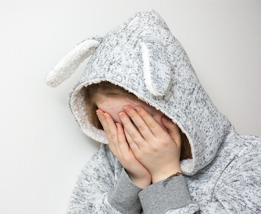 child hiding their face in their hands.