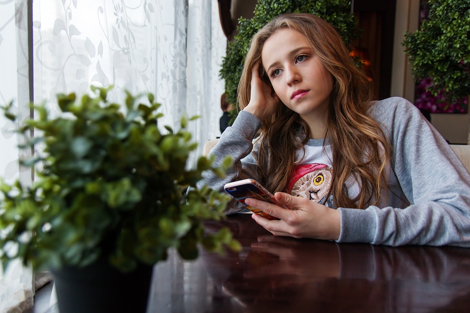 Girl looking worried holding mobile phone.